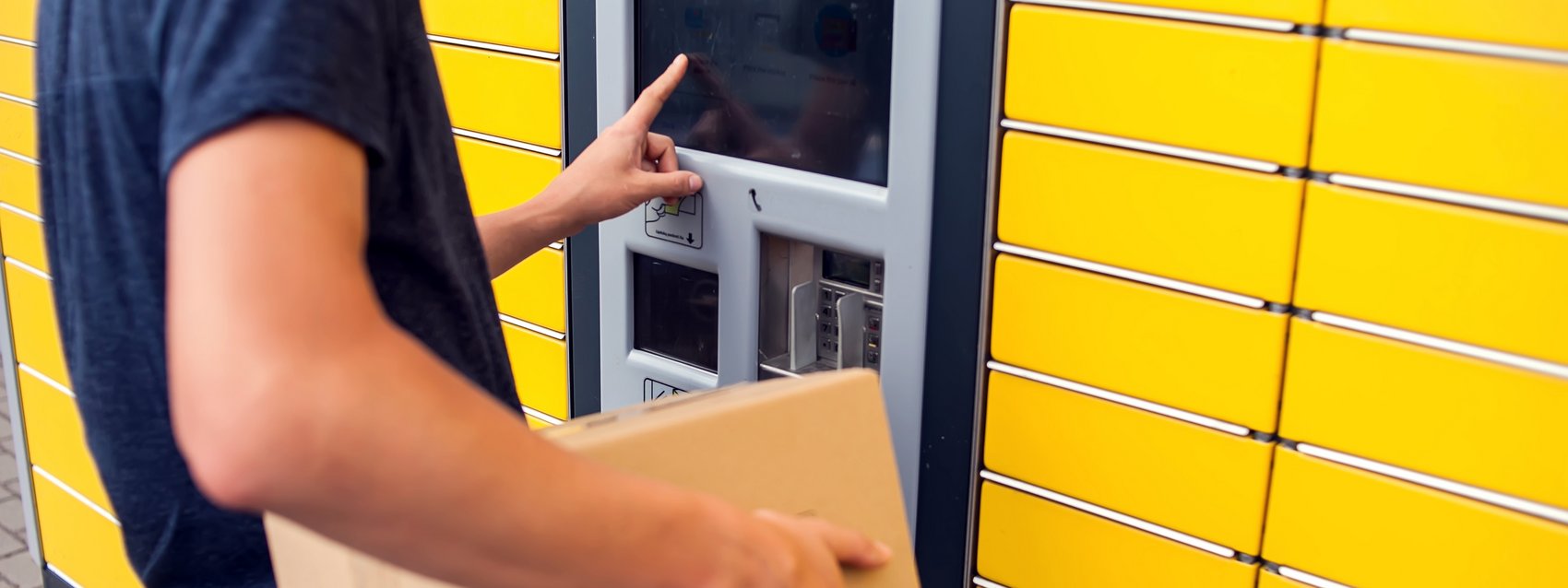 Mann an Packstation mit Paket in der Hand