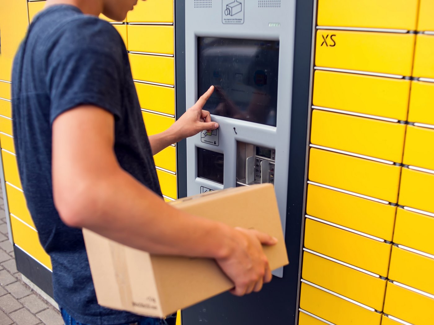Mann an Packstation mit Paket in der Hand