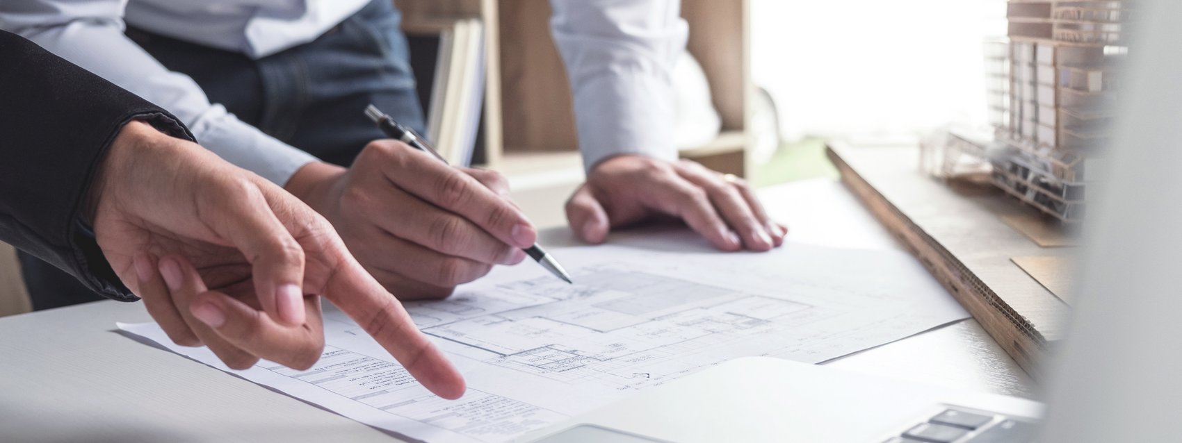 Engineering or Creative architect in construction project, Engineers hands working on construction blueprint and building model at a workplace in office, Building and architecture concept